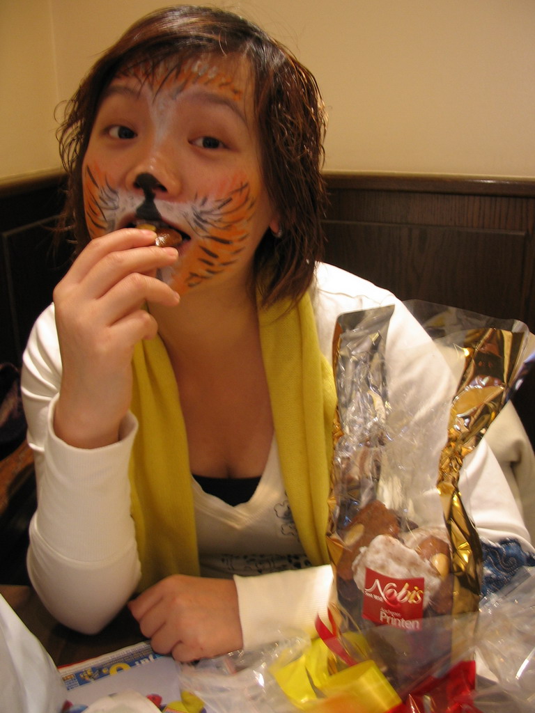 Miaomiao with face paint eating cookies at a restaurant in the city center