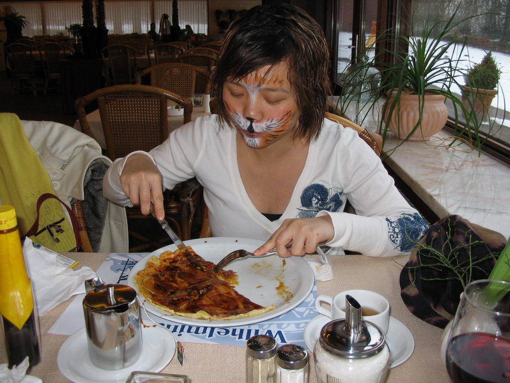 Miaomiao with face paint eating a pancake at the restaurant of the Wilhelminatoren tower at Vaals