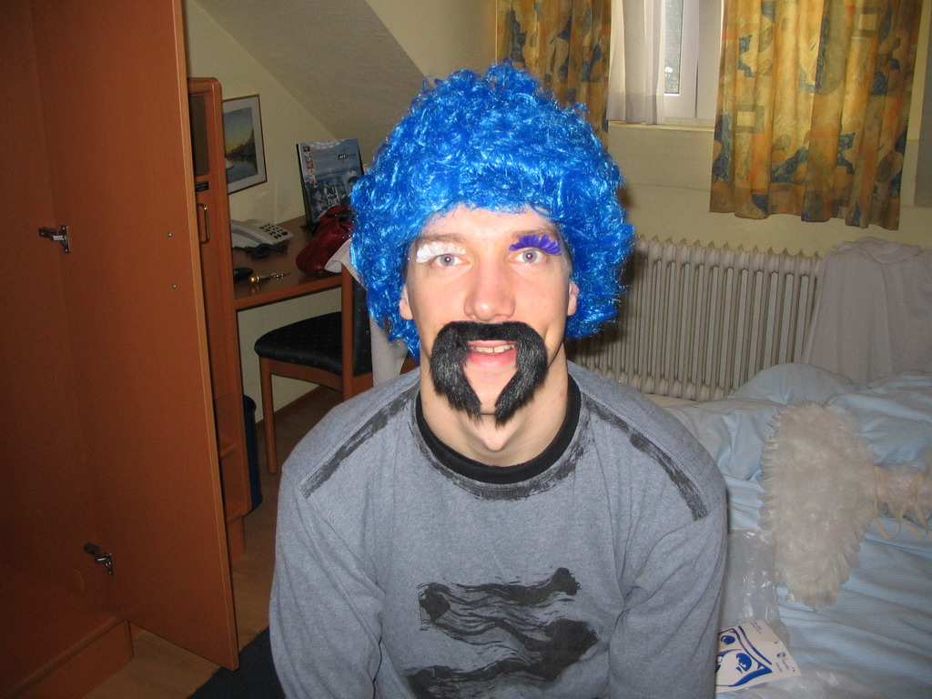 Tim with a wig, fake eyelashes and a fake mustache in our room at the Art Hotel Aachen