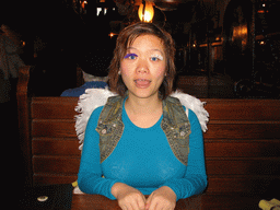 Miaomiao with fake eyelashes and angel wings at a restaurant in the city center