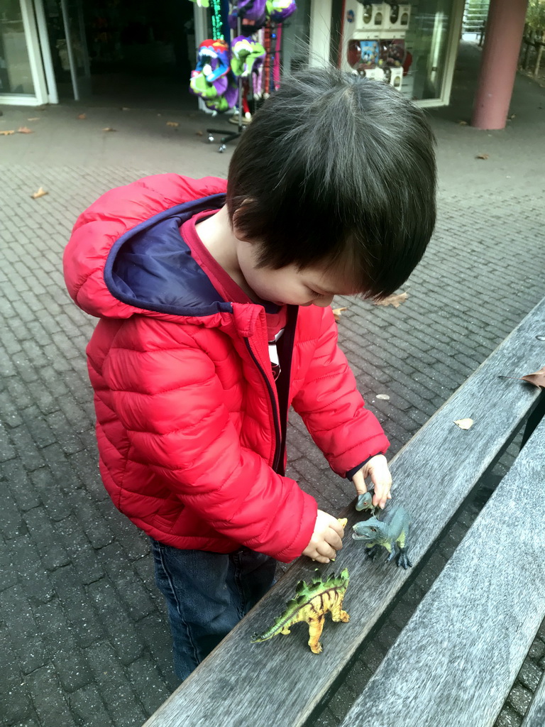 Max playing with dinosaur toys in front of the Jungleshop at the DierenPark Amersfoort zoo