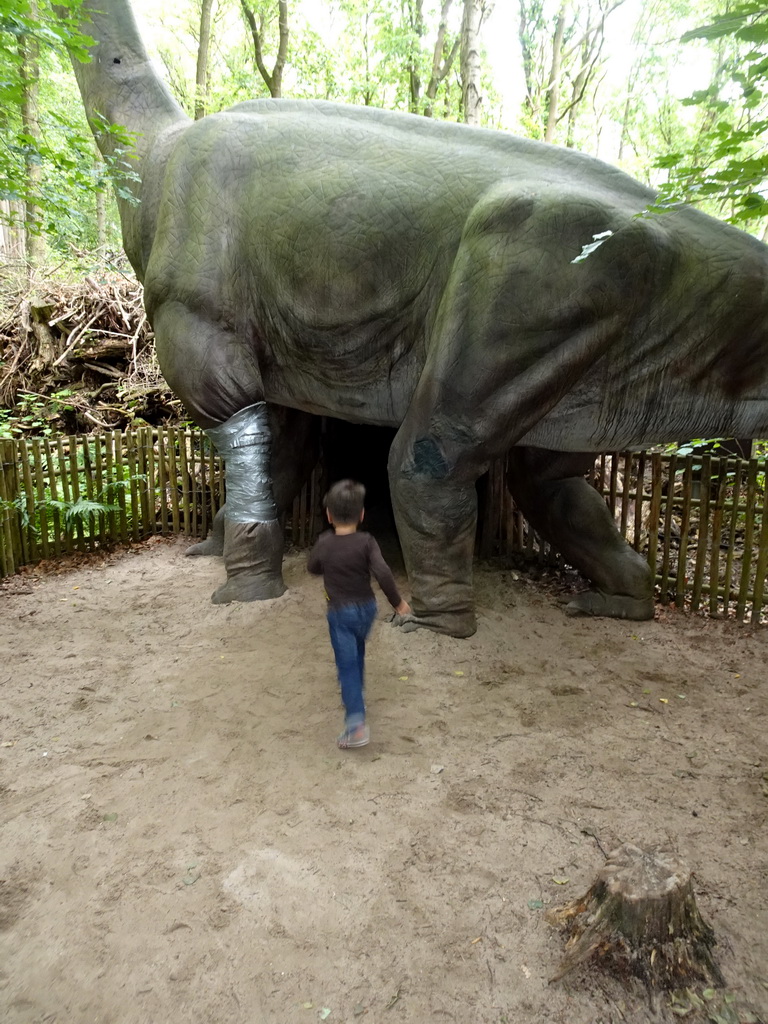 Max with a Brachiosaurus statue with a cave under it at the DinoPark at the DierenPark Amersfoort zoo