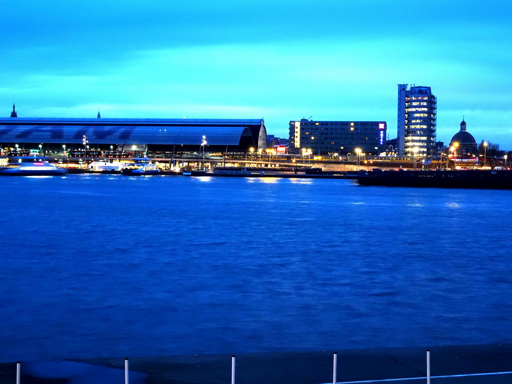 Boats in the IJ river, the Amsterdam Central Railway Station, the Hotel Ibis Amsterdam Centre, the Silver Tower and the Renaissance Koepelkerk conference center, viewed from the IJpromenade, at sunset