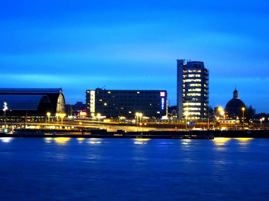 Boats in the IJ river, the Amsterdam Central Railway Station, the Hotel Ibis Amsterdam Centre, the Silver Tower and the Renaissance Koepelkerk conference center, viewed from the IJpromenade, at sunset