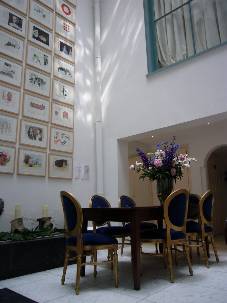 Table, chairs and a wall with art at a building at the Herengracht street