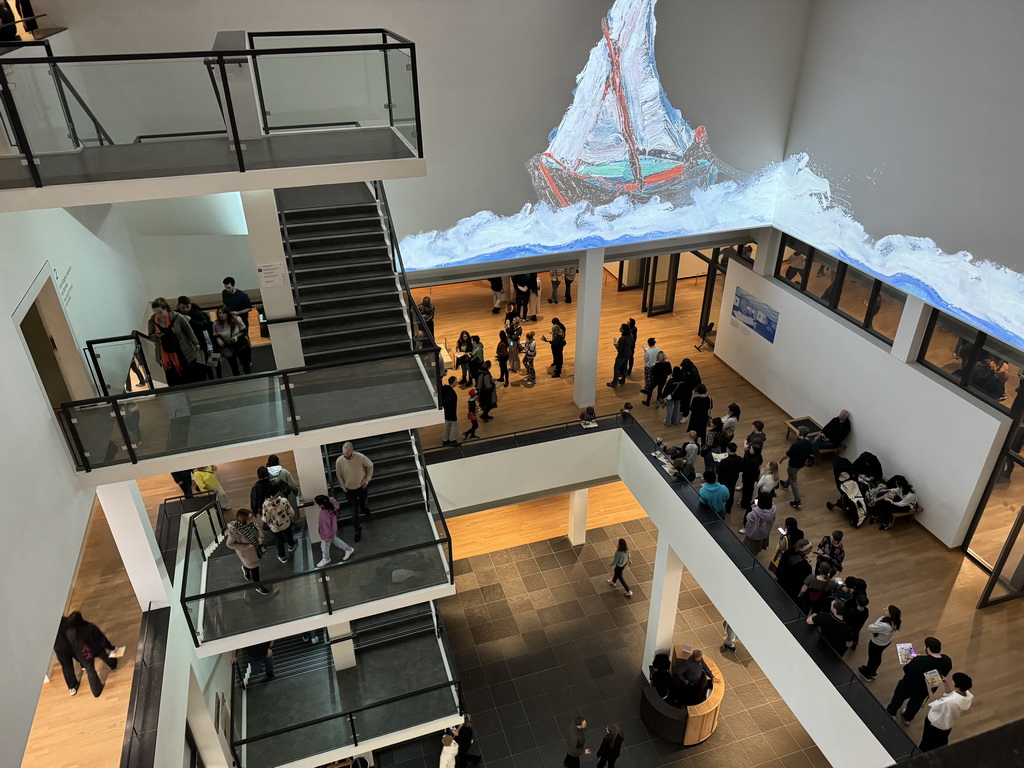 Projection at the upper floors and people waiting in line for the `Pokémon at the Van Gogh Museum` exhibition at the second floor of the Van Gogh Museum, viewed from the fourth floor