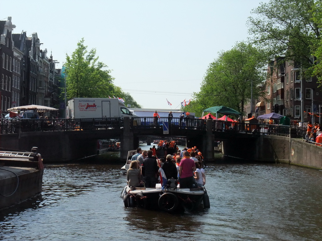 The Prinsengracht canal, with the bridge at the crossing of the Westermarkt square, and people with wooden shoes on a fishing pole