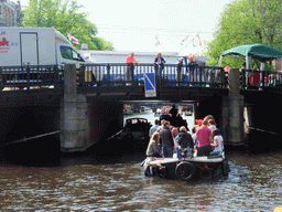 The Prinsengracht canal, with the bridge at the crossing of the Westermarkt square, and people with wooden shoes on a fishing pole