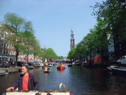 The skipper on the tour boat at the Prinsengracht canal, with the bridge at the crossing of the Westermarkt square and the Westerkerk church