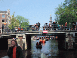 The skipper on the tour boat at the Prinsengracht canal, with the bridge at the crossing of the Reestraat street and the Westerkerk church