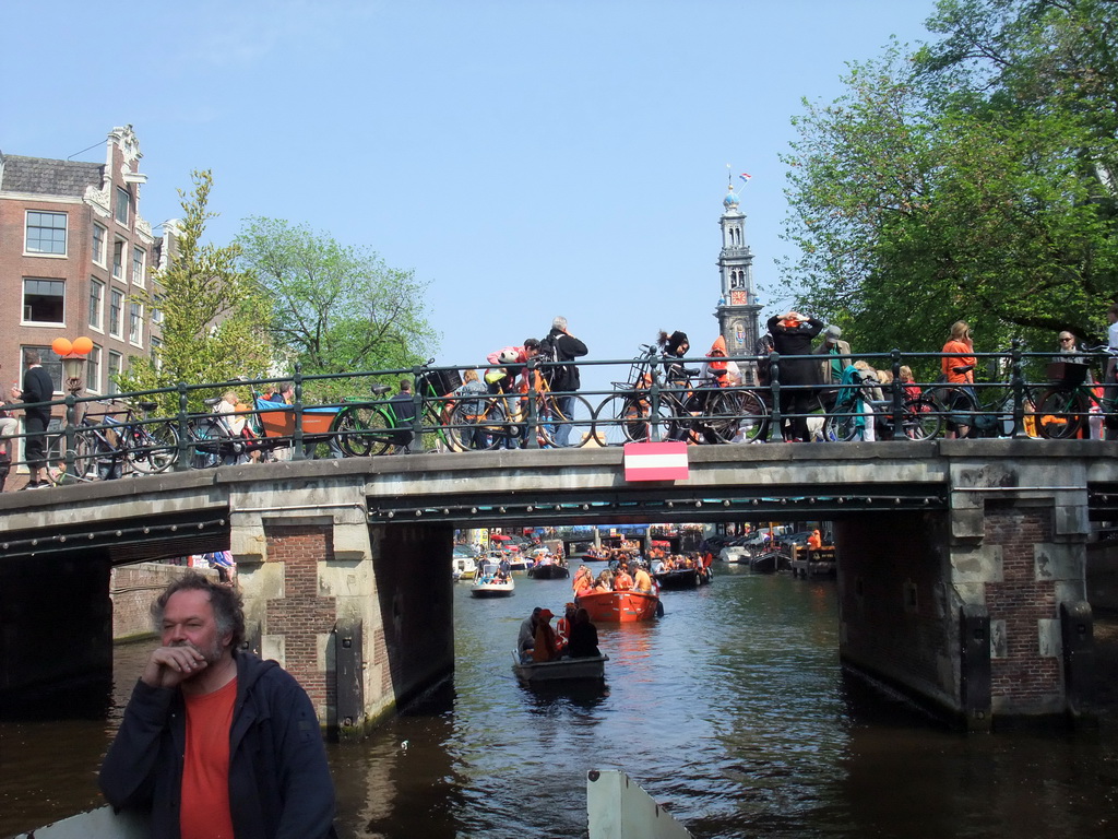 The skipper on the tour boat at the Prinsengracht canal, with the bridge at the crossing of the Reestraat street and the Westerkerk church