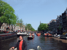The skipper on the tour boat at the Prinsengracht canal, with the bridge at the crossing of the Reestraat street and the Westerkerk church