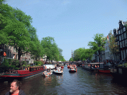 The skipper on the tour boat at the Prinsengracht canal, with the bridge at the crossing of the Berenstraat street and the Westerkerk church