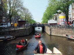 The skipper on the tour boat at the Prinsengracht canal, with the bridge at the crossing of the Utrechtsestraat street