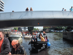 The skipper on the tour boat at the Westerdok canal with the Han Lammersbrug bridge