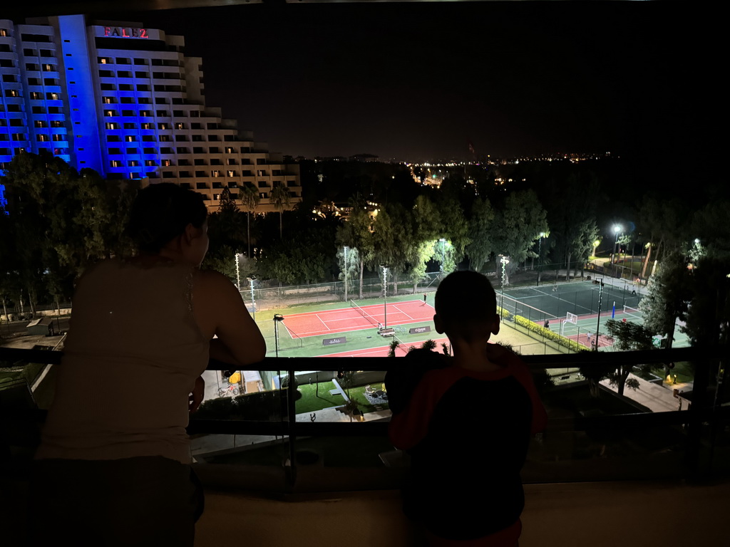 Miaomiao and Max at the balcony of our room at the Rixos Downtown Antalya hotel, with a view on the Sports fields and the Özkaymak Falez Hotel, by night