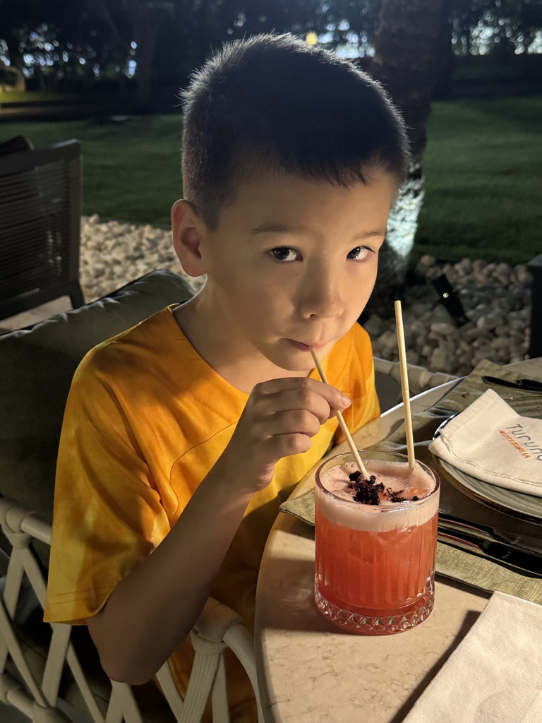 Max with a mocktail at the terrace of the Turunc restaurant at the garden of the Rixos Downtown Antalya hotel, by night