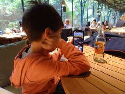 Max watching iPhone at the terrace of the Bush Restaurant at the Bush Hall of Burgers` Zoo