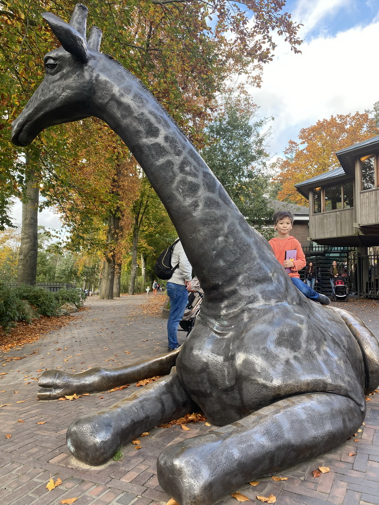 Max on the Giraffe statue at the entrance to Burgers` Zoo at the Antoon van Hooffplein square