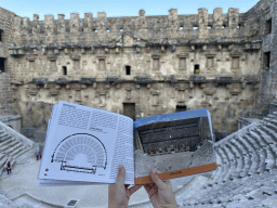 Impression of the original look in a travel guide at the diazoma of the west auditorium of the Roman Theatre of Aspendos, with a view on the orchestra, stage and stage building