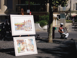 Drawings and street musician at the Place de l`Horloge square
