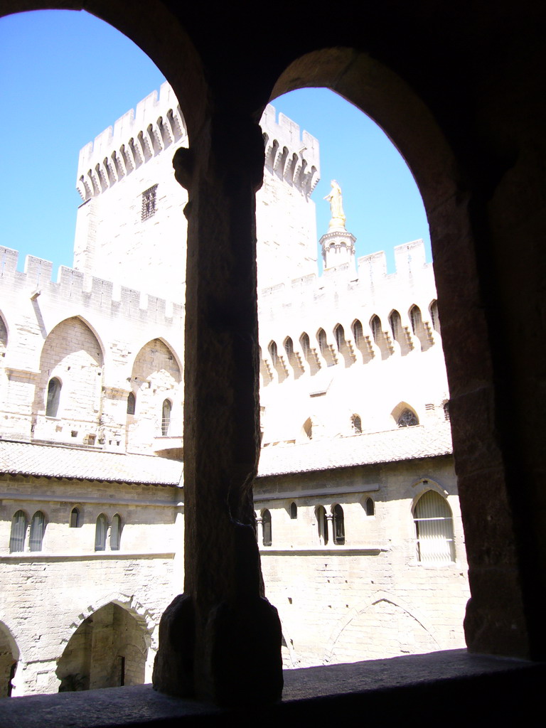 Window with a view on the Cloister at the Palais des Papes palace, and the Gilded statue of the Virgin Mary at the top of the Avignon Cathedral