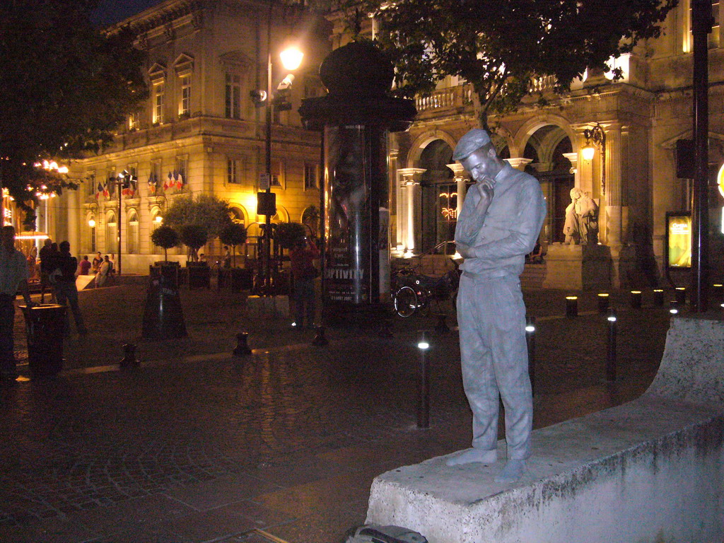 Living statue in front of the Opera Grand Avignon at the Place de l`Horloge square, by night