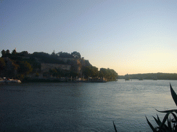 The Pont Saint-Bénezet bridge over the Rhône river, the Rocher des Doms gardens and the Gilded statue of the Virgin Mary at the top of the Avignon Cathedral, viewed from the Restaurant Le Bercail at the Chemin des Canotiers street, at sunset