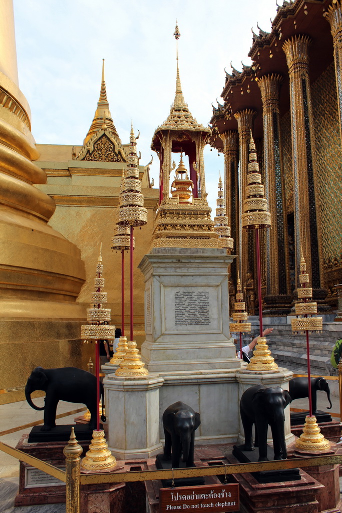 Column with elephants in front of the Phra Siratana Chedi stupa and the Phra Mondop hall at the Temple of the Emerald Buddha at the Grand Palace