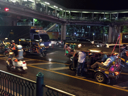 Rickshaws, cars and skywalk at Cha Loem Pao Junction, by night
