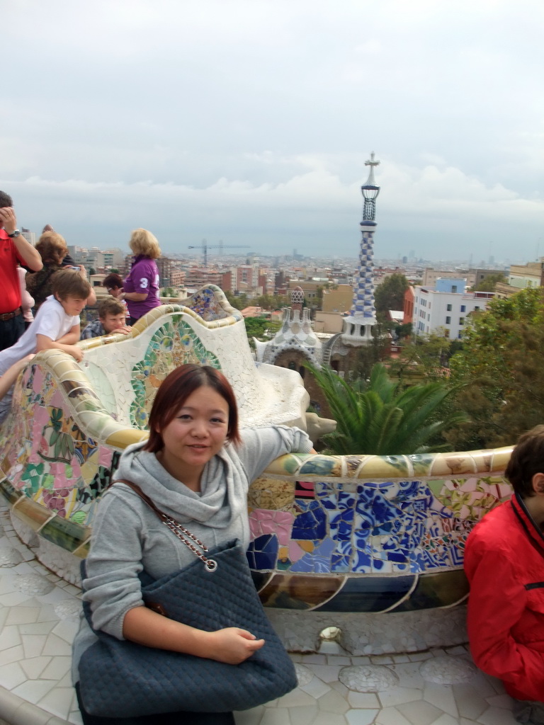 Miaomiao at the Square of Nature at Park Güell, with a view on the tower of the west entrance building and the city center