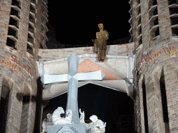 Cross and statue on top of the Passion Facade at the southwest side of the Sagrada Família church, viewed from the Plaça de la Sagrada Família square, by night