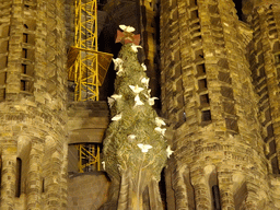 Statue of a tree with doves at the Nativity Facade at the northeast side of the Sagrada Família church, viewed from the Carrer de la Marina street, by night