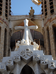 Cross and statue on top of the Passion Facade at the southwest side of the Sagrada Família church, viewed from the Plaça de la Sagrada Família square