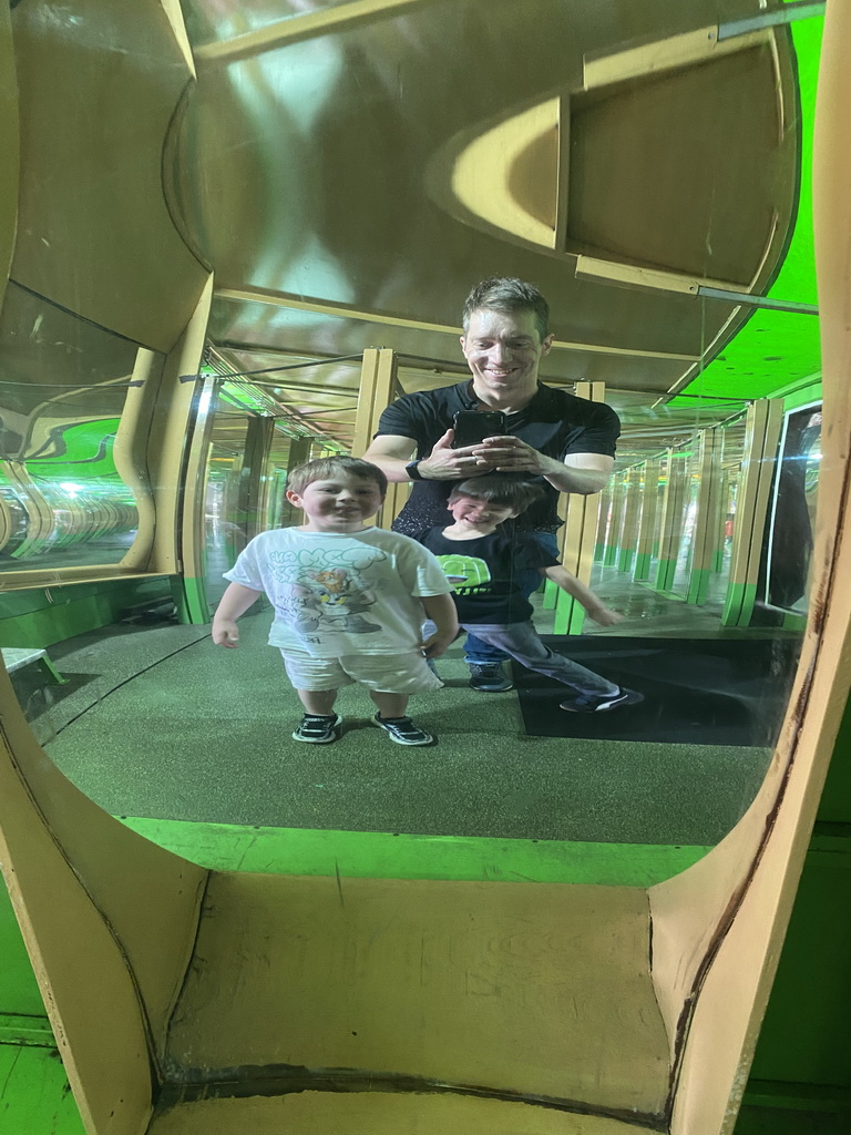 Tim, Max and Max`s friend in a distorting mirror at the Rainforest Mirror Maze attraction at the funfair at the Brigidastraat street