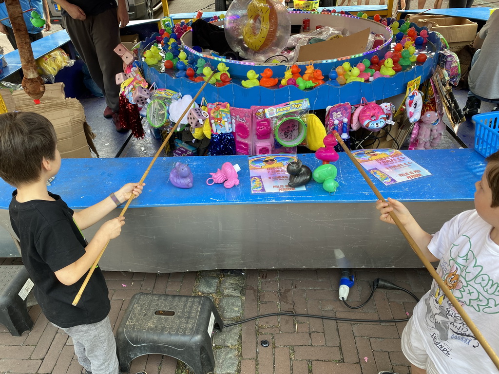 Max and his friend doing a fishing game at the funfair at the Jack van Gilsplein square