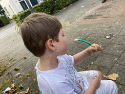 Max`s friend with a lollipop on a bench at the funfair at the Jack van Gilsplein square