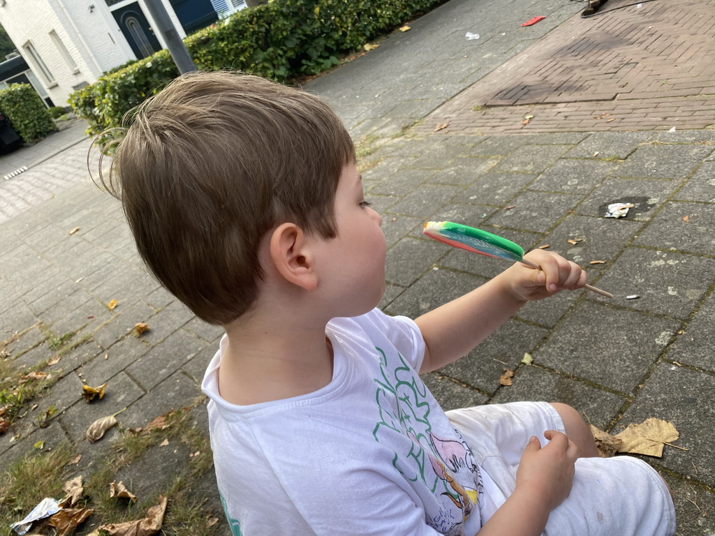 Max`s friend with a lollipop on a bench at the funfair at the Jack van Gilsplein square