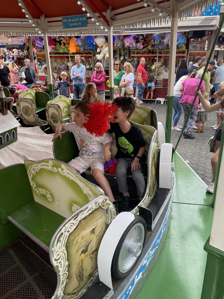 Max and his friend with a plume at a carousel at the funfair at the Brigidastraat street