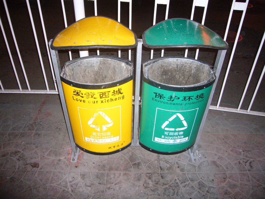 Trash cans with Chinglish explanation, by night