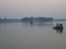 Boats at the east side of Kunming Lake, the Seventeen-Arch Bridge and South Lake Island with the Hall Of Embracing The Universe at the Summer Palace, viewed from the north side, at sunset