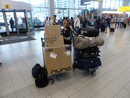 Miaomiao and Max with suitcases and boxes with babyfood, at the Departure Hall of Schiphol Airport
