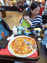 Miaomiao and Max with a pizza at a restaurant at Schiphol Airport