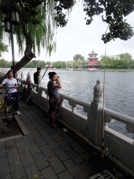 Fishermen at the Houhai Nanyan street, with a view on Houhai Lake and the pavilion at the Houhai Beiyan street