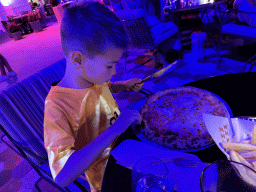 Max eating Pizza Margherita at the terrace of the Piazzetta Italiana restaurant at the Shopping Avenue area of the Land of Legends theme park, at sunset