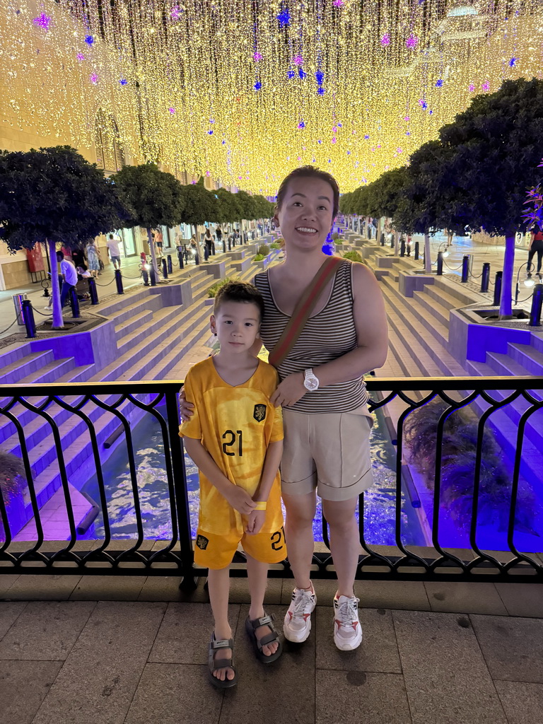 Miaomiao and Max on a bridge over the canal at the Shopping Avenue area of the Land of Legends theme park, by night