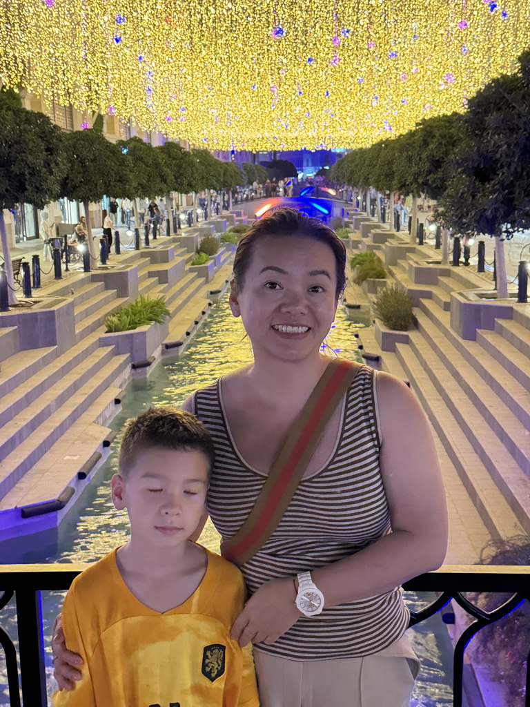 Miaomiao and Max on a bridge over the canal at the Shopping Avenue area of the Land of Legends theme park, by night