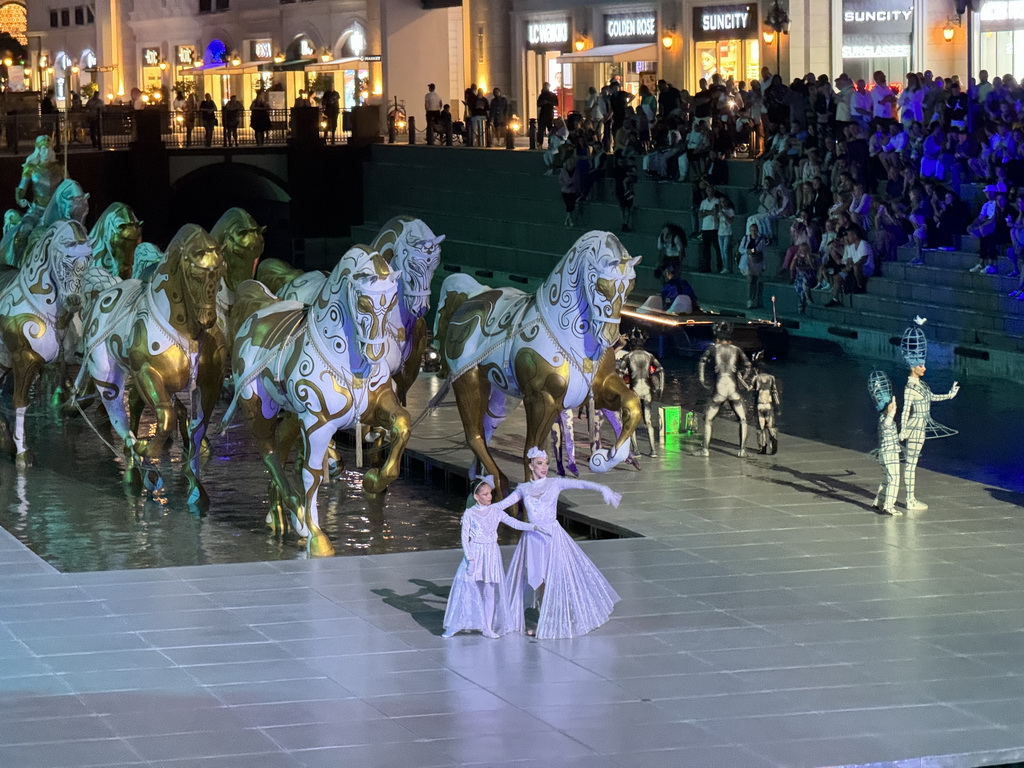 Actors and horse statues in front of the Chateau at the Shopping Avenue area of the Land of Legends theme park, during the Musical Boat Parade, by night