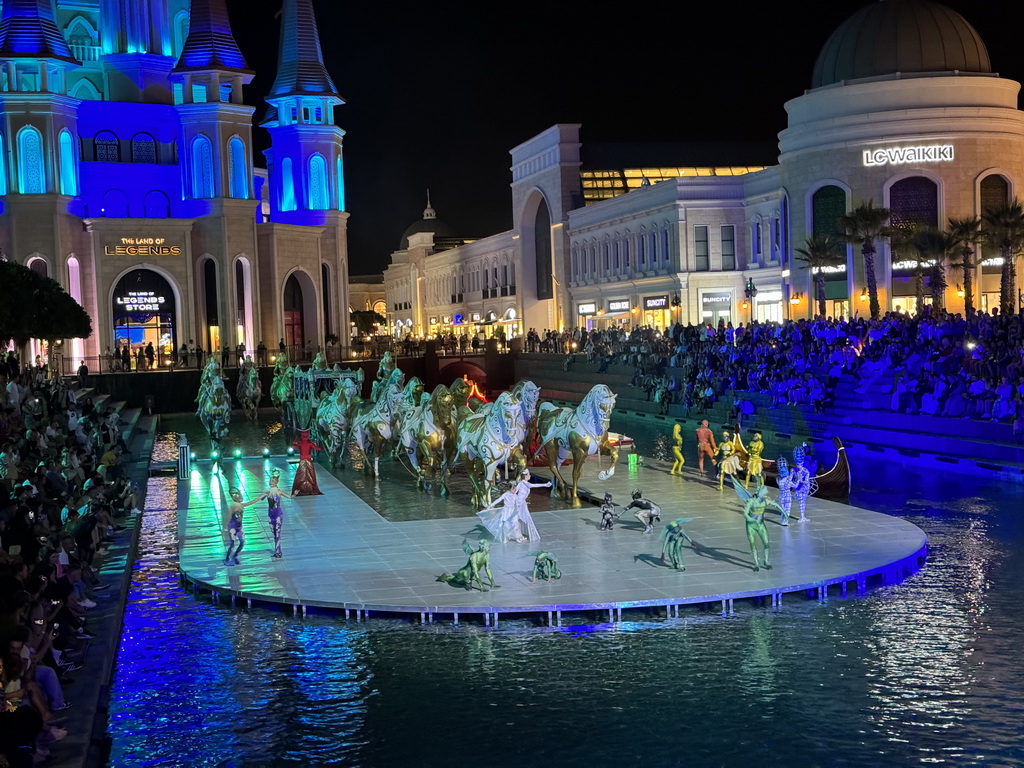 Boats, actors and horse statues in front of the Chateau at the Shopping Avenue area of the Land of Legends theme park, during the Musical Boat Parade, by night