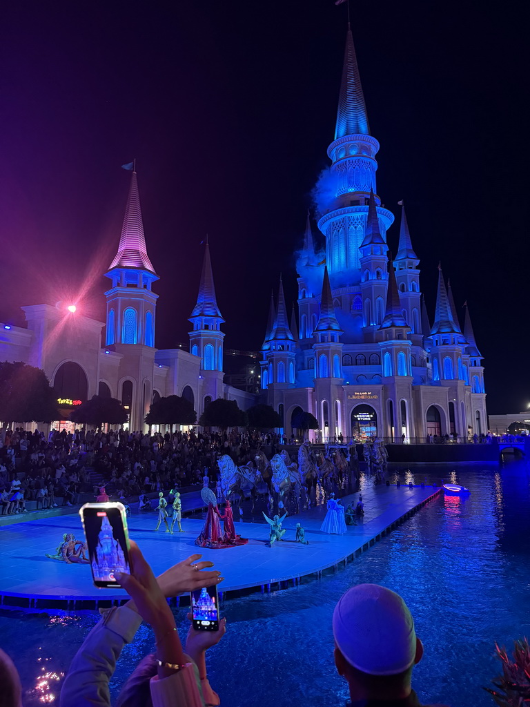 Boats, actors and horse statues in front of the Chateau at the Shopping Avenue area of the Land of Legends theme park, during the Musical Boat Parade, by night